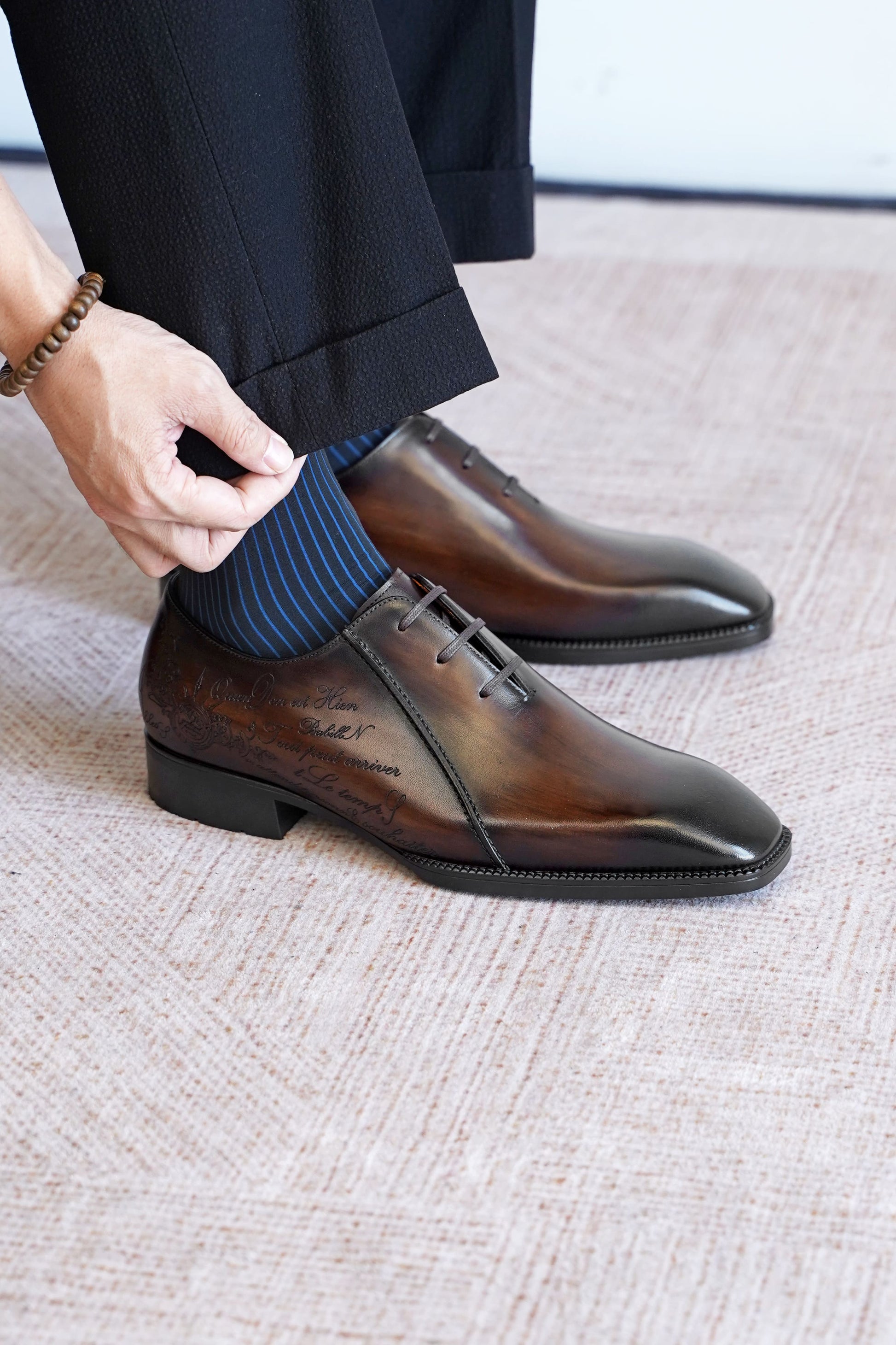 Men’s dark brown leather Oxford dress shoes with lace-up design, polished finish, pointed toe silhouette, and embossed script detail on the side panel.