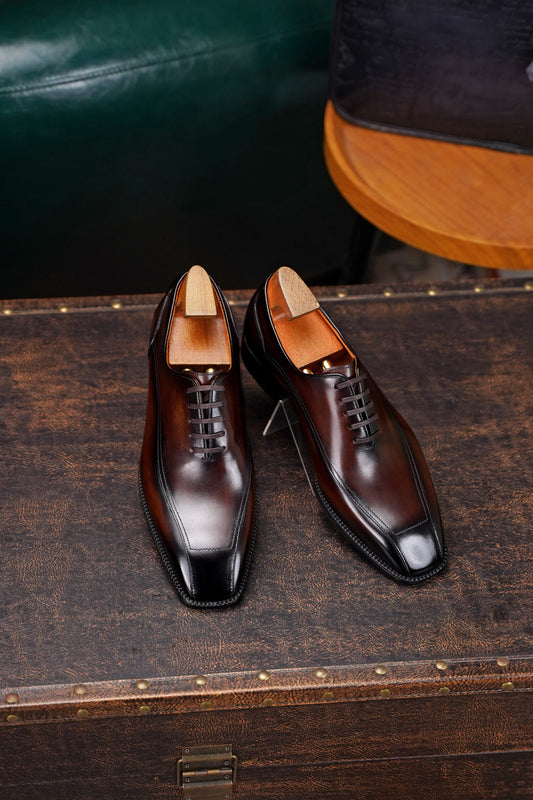 Men’s dark brown leather wholecut Oxford dress shoes with sleek lace-up design and polished formal finish.