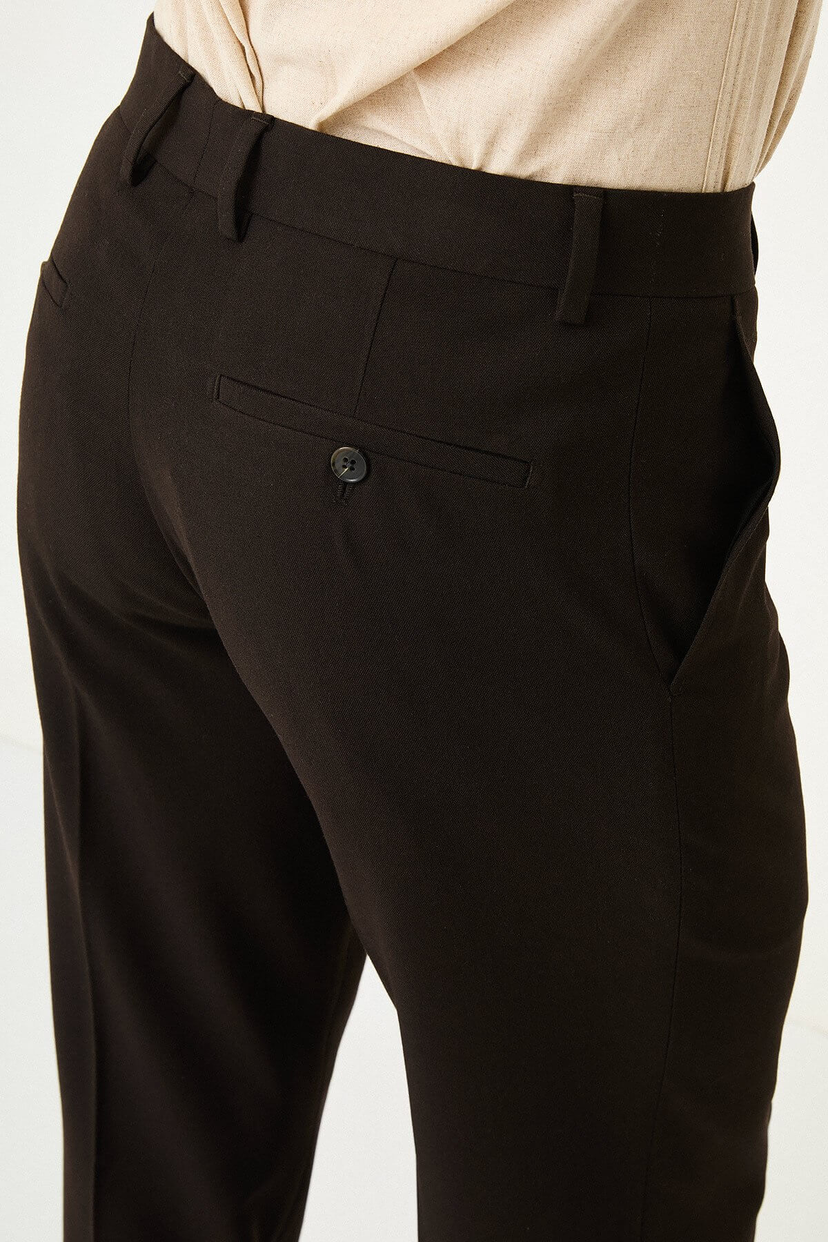 Dark brown slim-fit formal trousers with front pleats, paired with brown leather shoes.