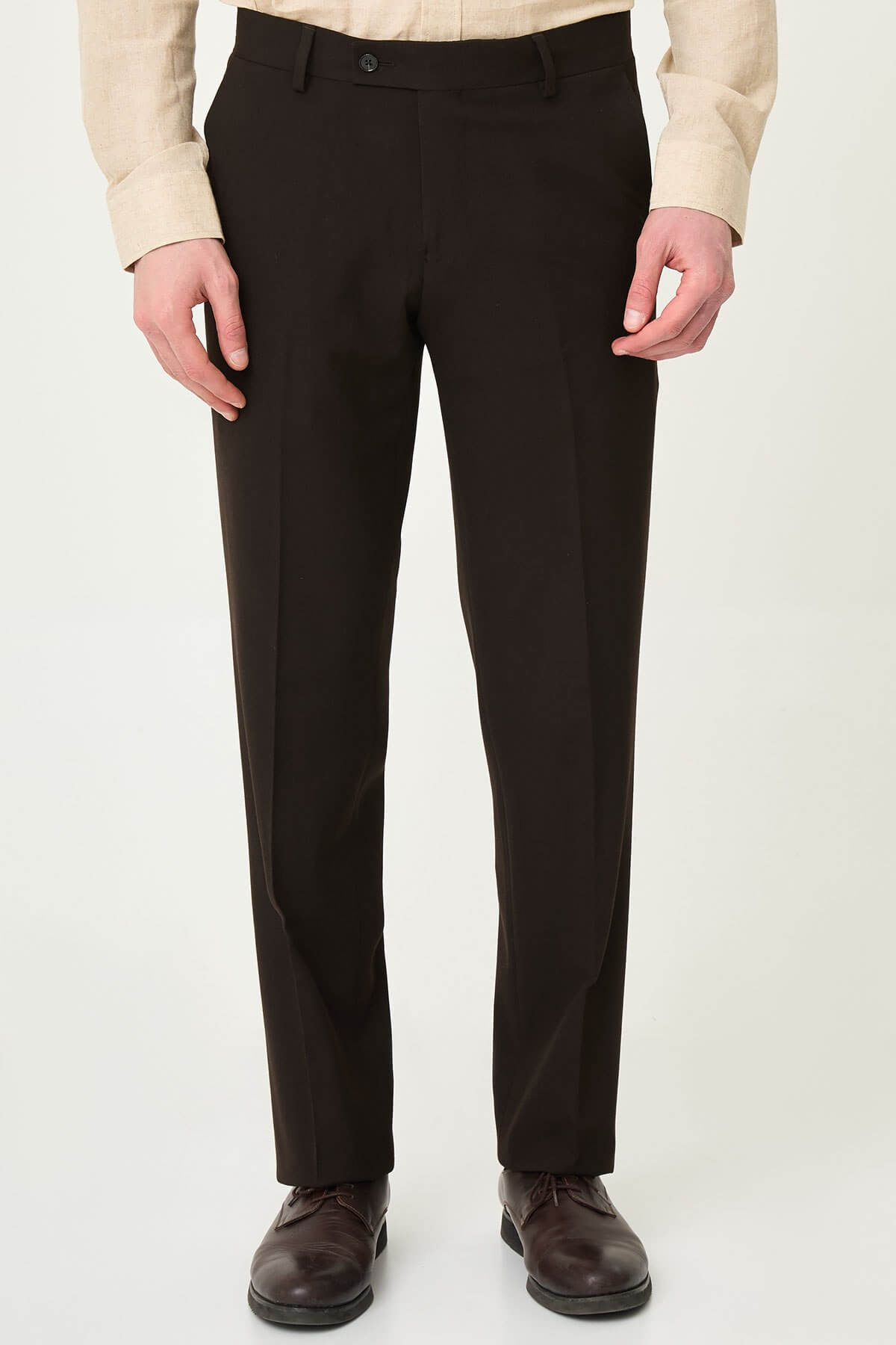 Dark brown slim-fit formal trousers with front pleats, paired with brown leather shoes.