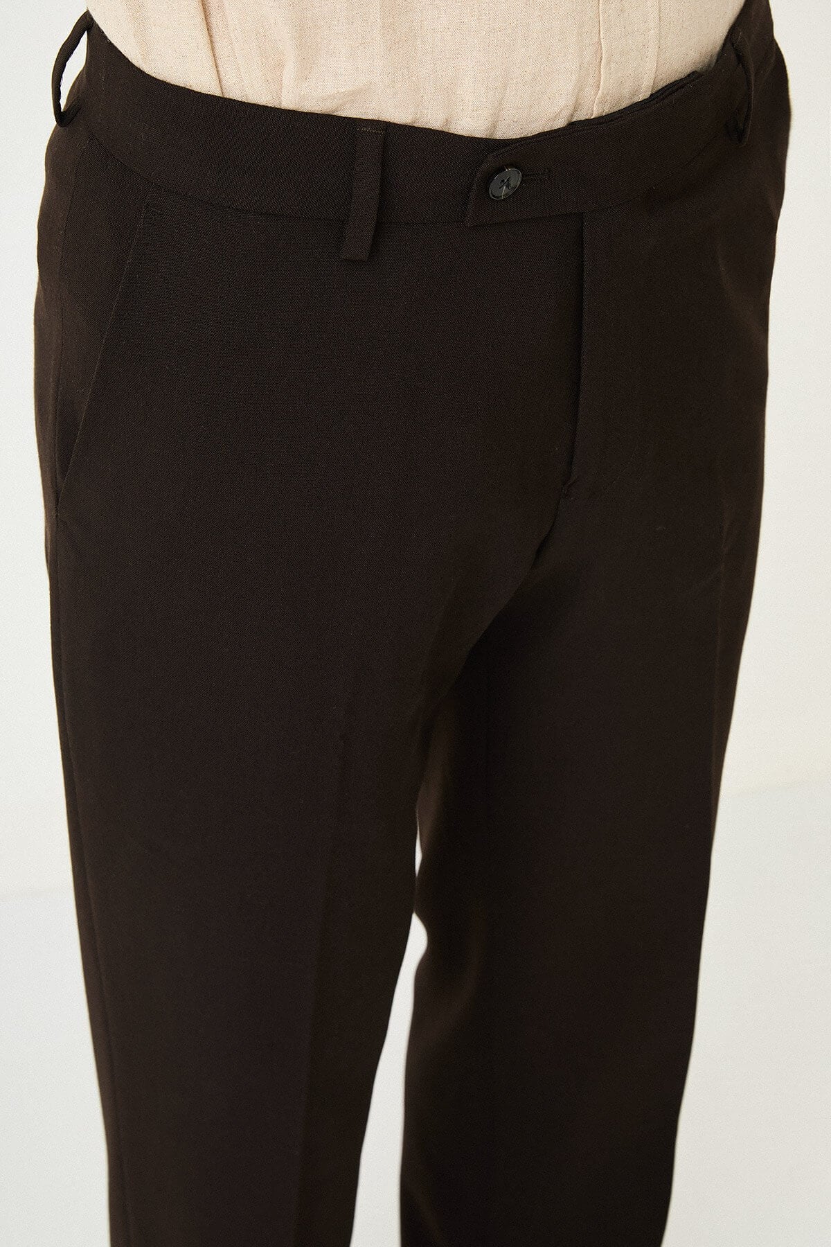 Dark brown slim-fit formal trousers with front pleats, paired with brown leather shoes.
