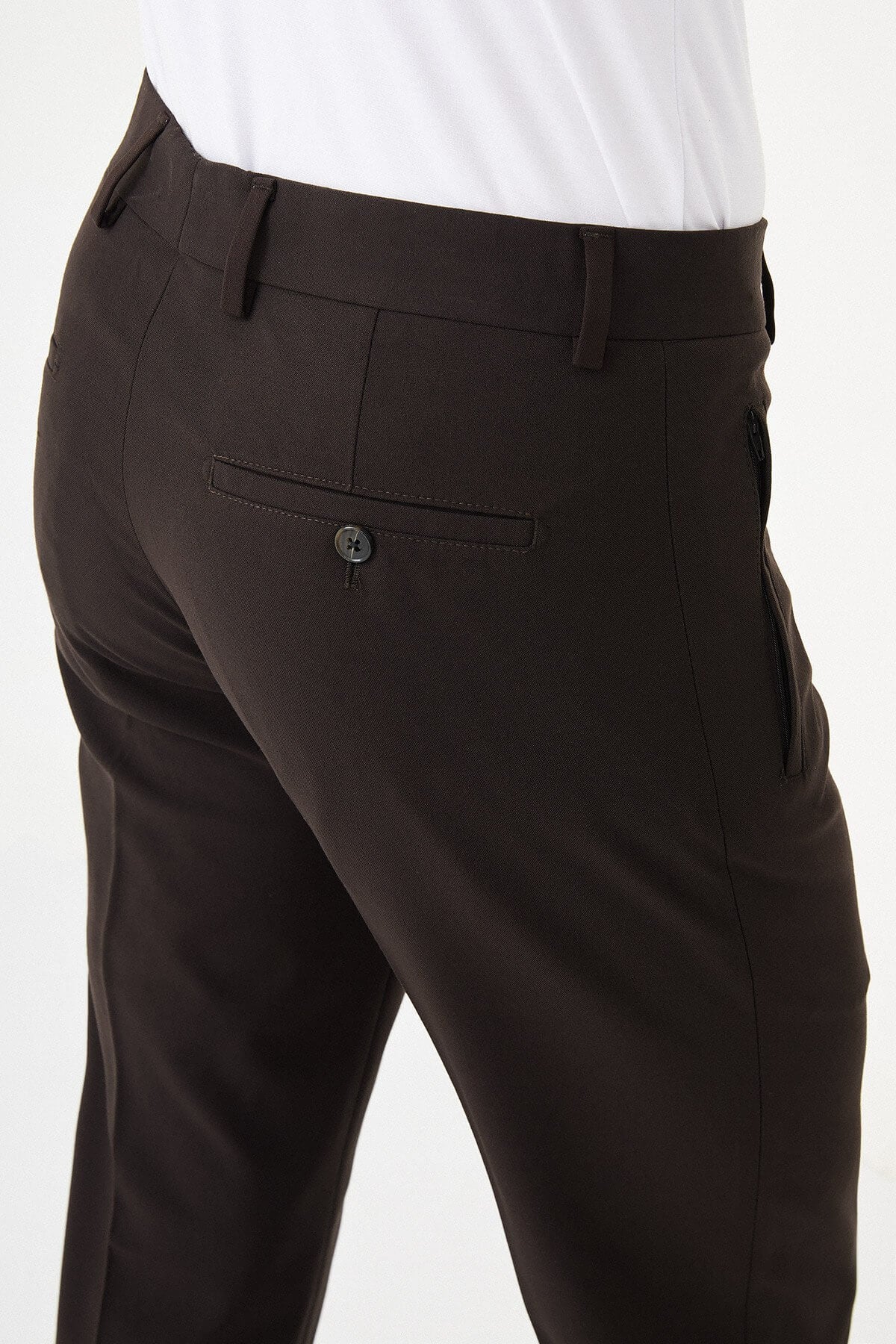 Man wearing dark brown slim-fit dress trousers styled with a white shirt and brown leather shoes.