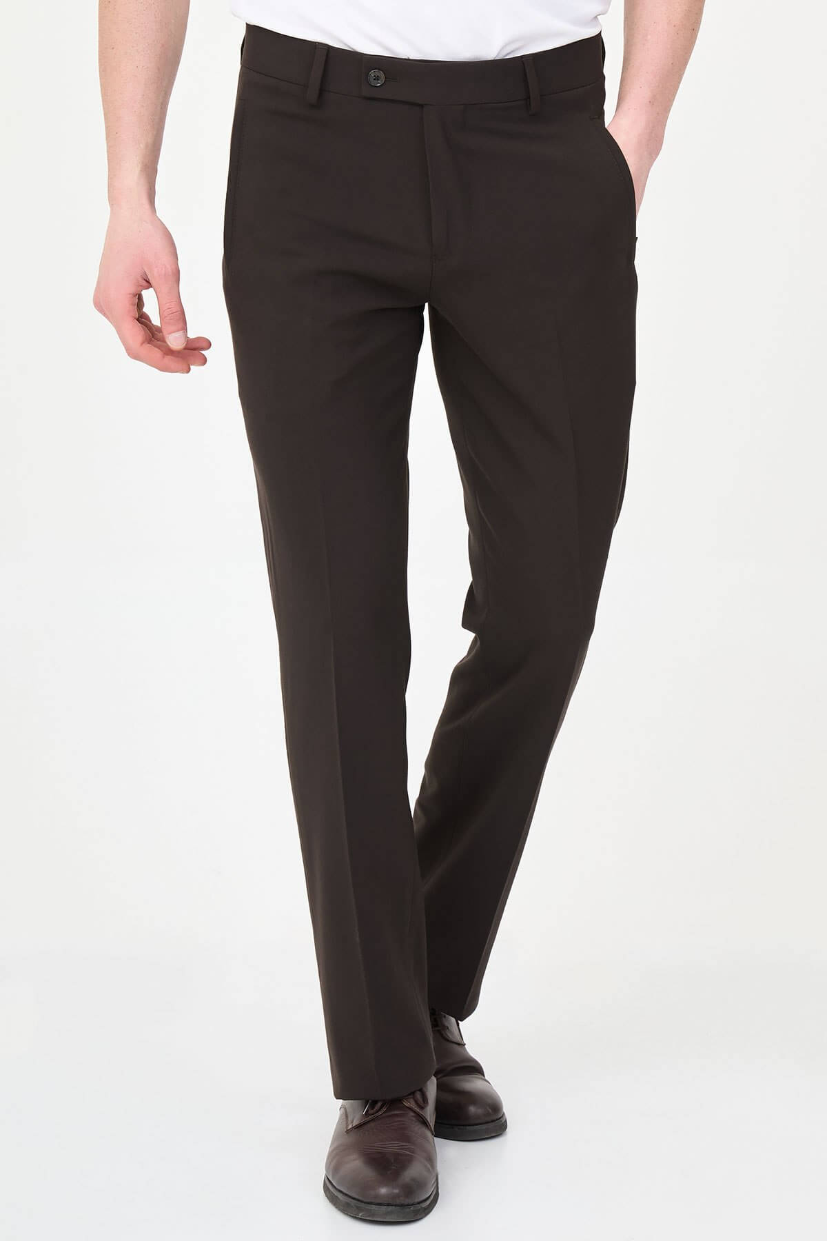 Man wearing dark brown slim-fit dress trousers styled with a white shirt and brown leather shoes.