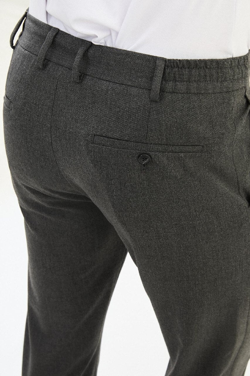Men wearing dark gray slim-fit drawstring trousers with elastic waistband, casual-formal hybrid, styled with sneakers and dress shoes for versatile summer menswear.