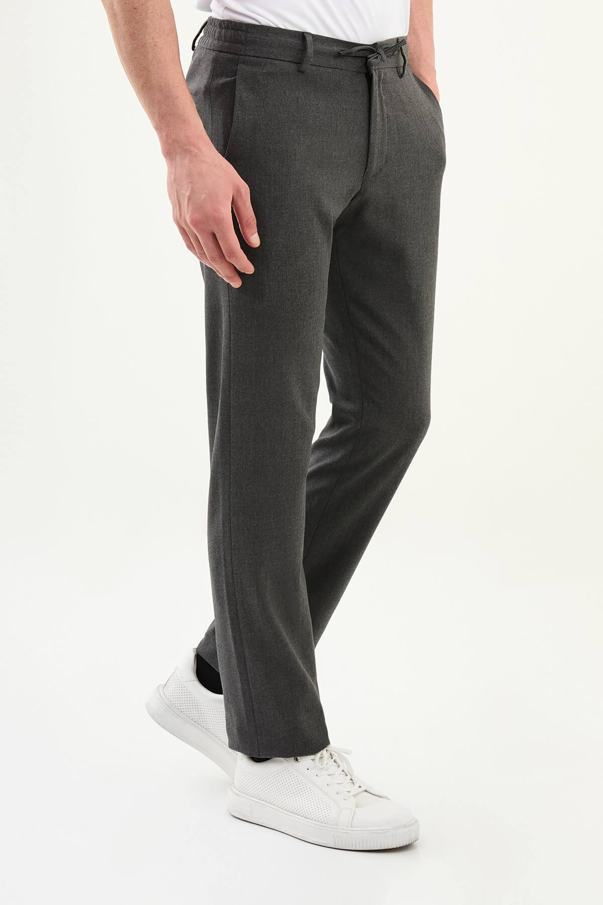 Men wearing dark gray slim-fit drawstring trousers with elastic waistband, casual-formal hybrid, styled with sneakers and dress shoes for versatile summer menswear.