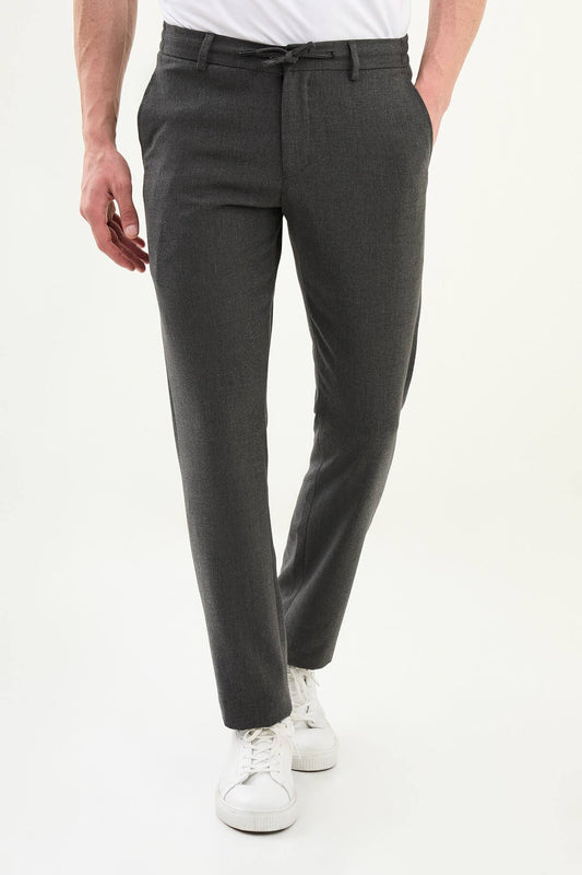 Men wearing dark gray slim-fit drawstring trousers with elastic waistband, casual-formal hybrid, styled with sneakers and dress shoes for versatile summer menswear.