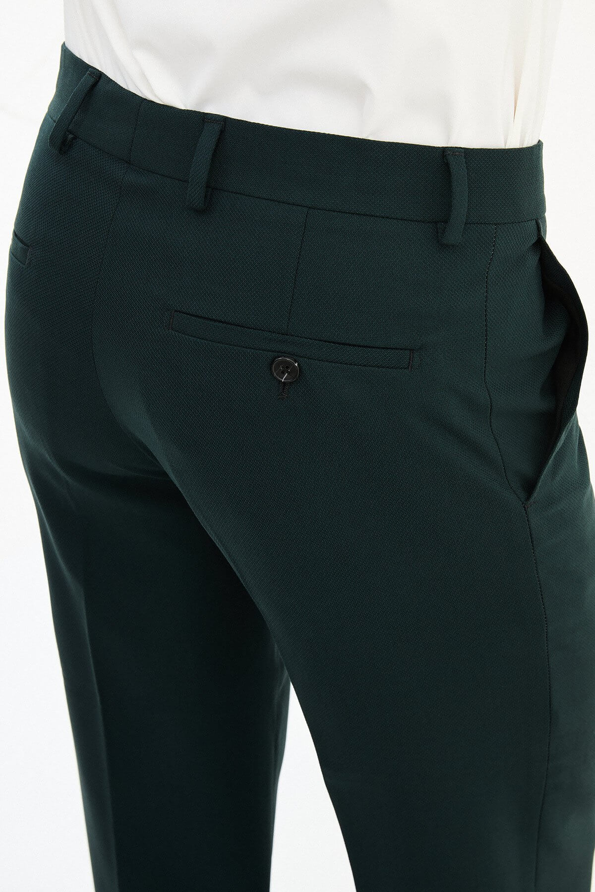 Man wearing dark green pleated dress trousers with straight slim fit, styled with a white dress shirt and brown leather shoes.