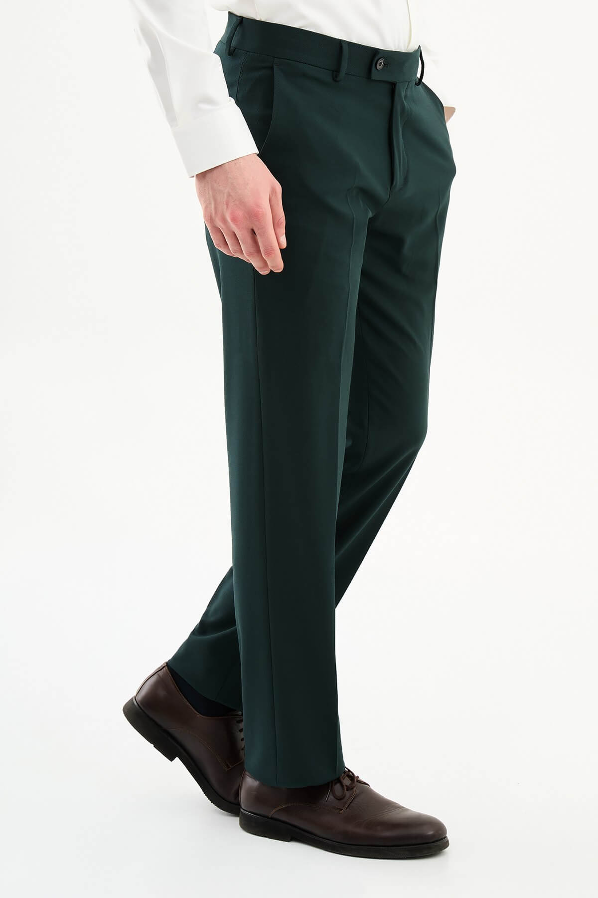 Man wearing dark green pleated dress trousers with straight slim fit, styled with a white dress shirt and brown leather shoes.