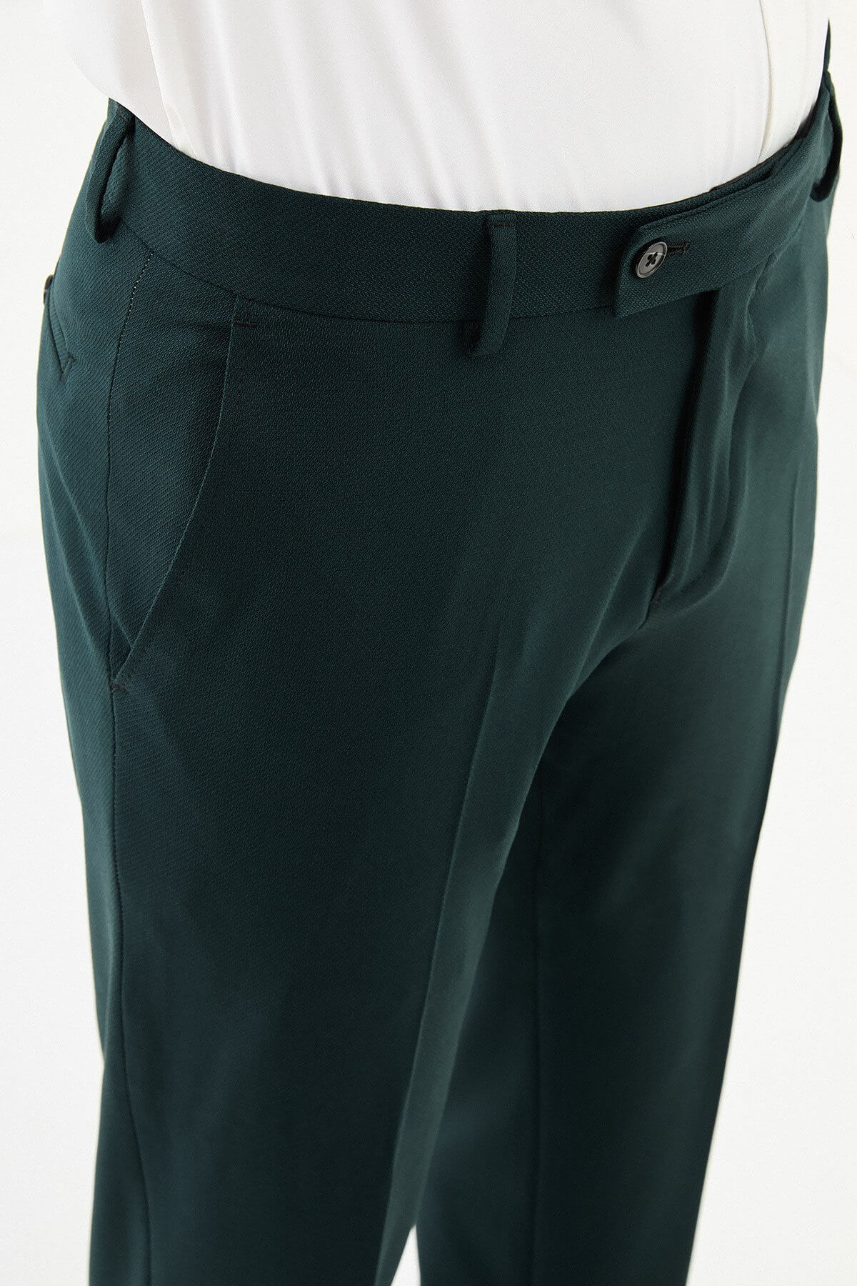 Man wearing dark green pleated dress trousers with straight slim fit, styled with a white dress shirt and brown leather shoes.