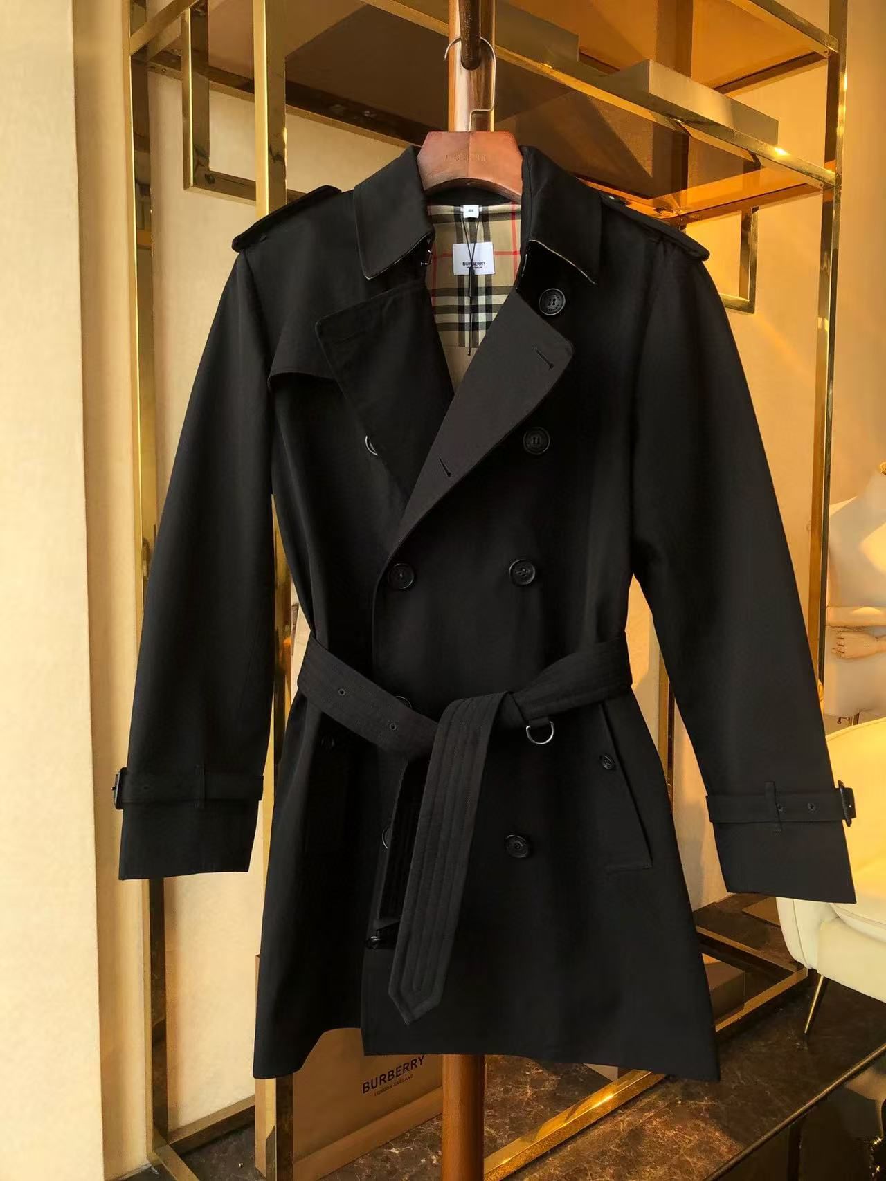 Black trench coat with a double-breasted design and adjustable belt