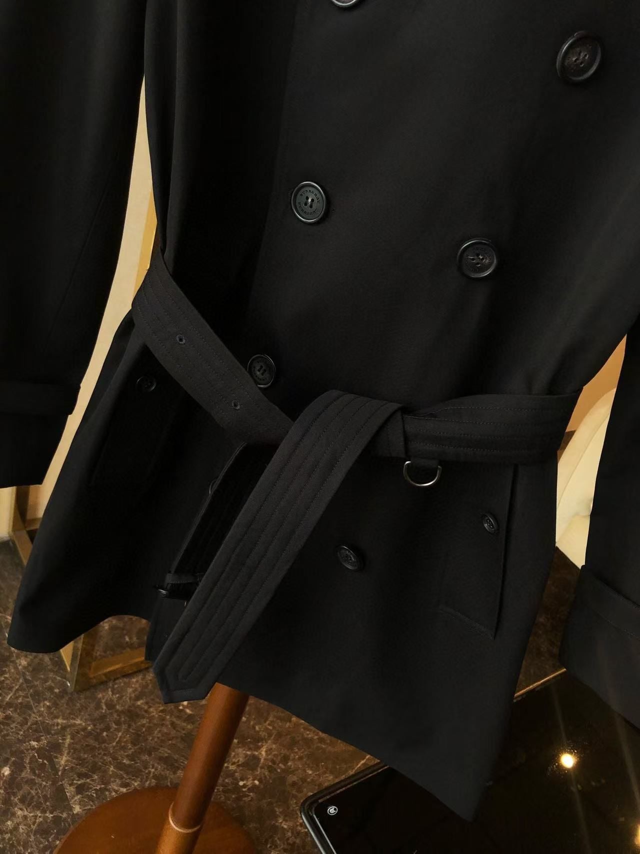 Black trench coat with a double-breasted design and adjustable belt