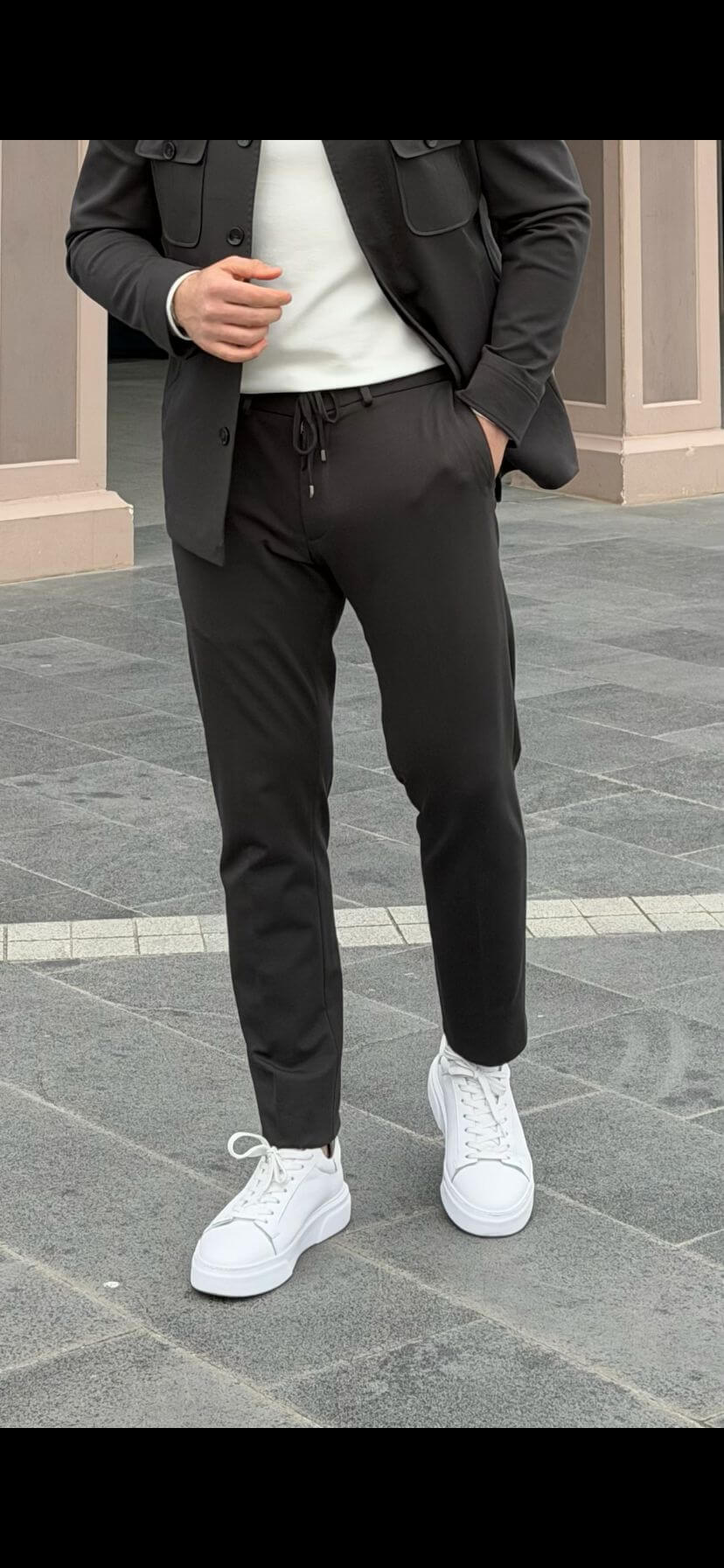 Men’s khaki elastic waist drawstring pants with tapered fit styled with white sneakers and smart casual jacket