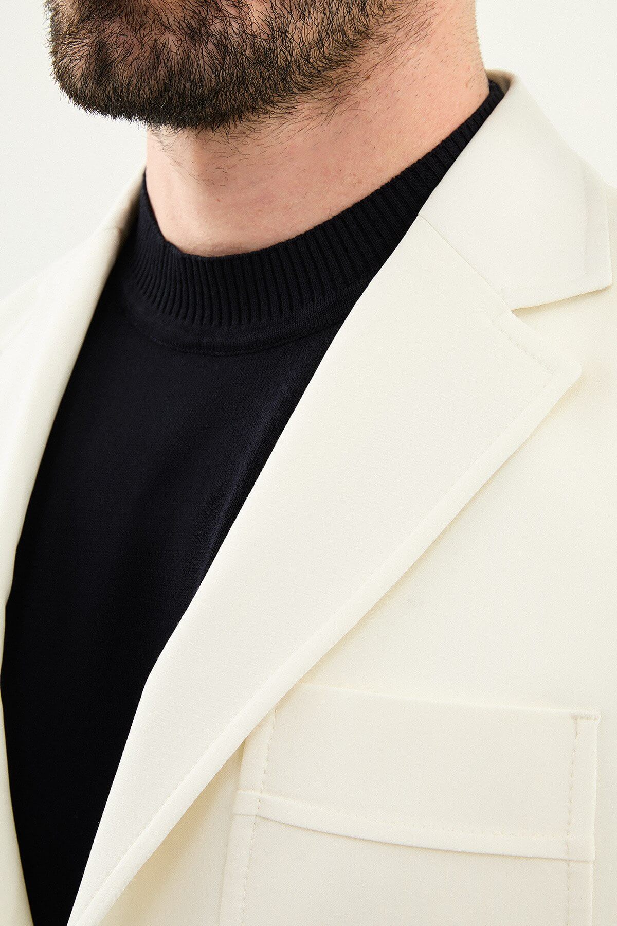 Men’s ecru slim fit blazer with a clean minimalist design and stretch fabric, styled with a black knit top for elegant smart casual and formal looks.