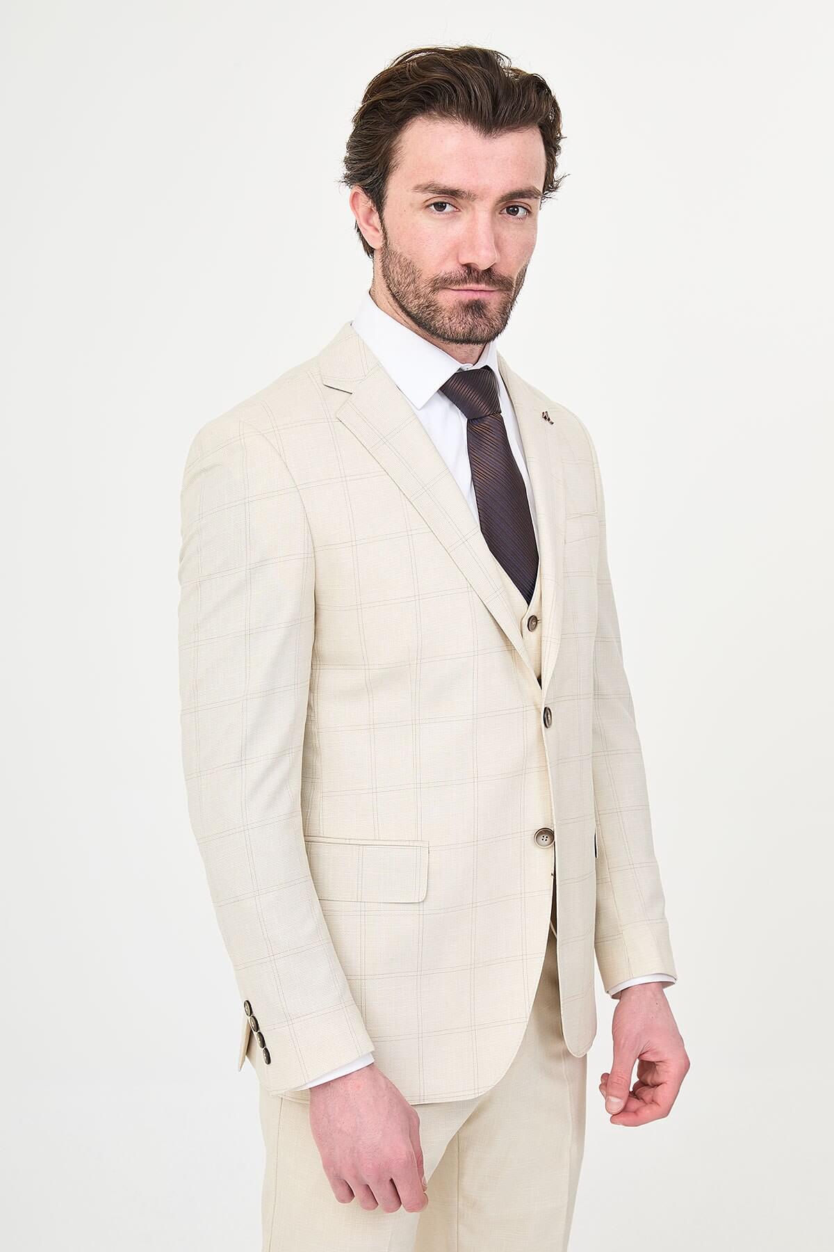 an ecru check slim-fit three-piece suit with matching waistcoat and trousers, white dress shirt, dark brown tie, and brown leather Derby shoes.