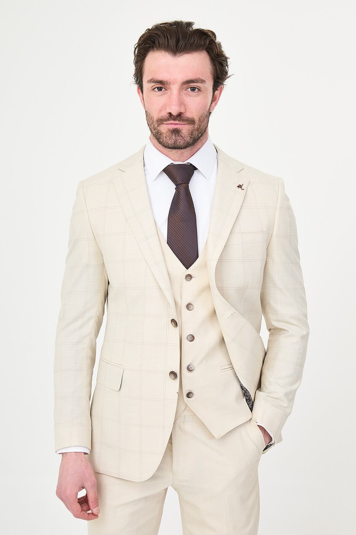 an ecru check slim-fit three-piece suit with matching waistcoat and trousers, white dress shirt, dark brown tie, and brown leather Derby shoes.
