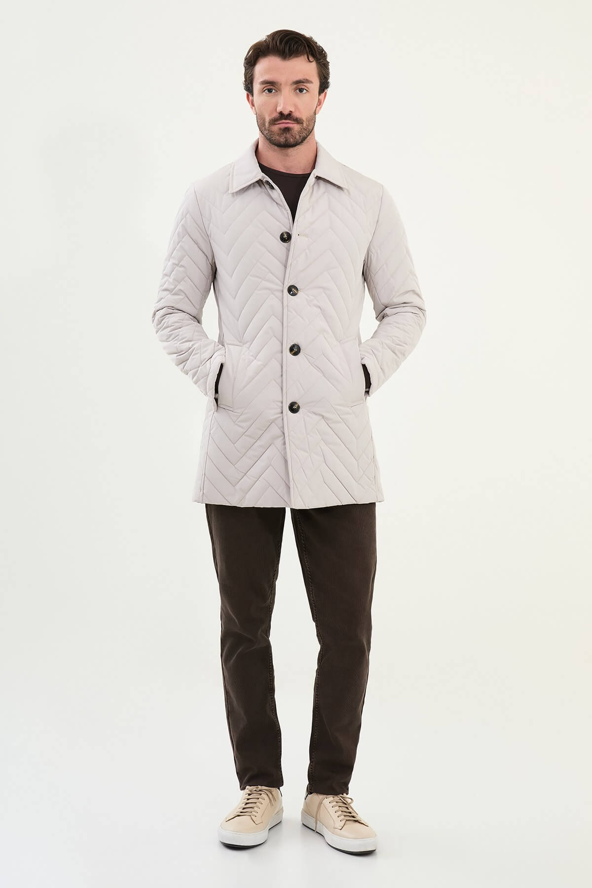 Men’s Ecru Quilted Slim Fit Car Coat with chevron stitching and button closure, styled with dark brown trousers and beige sneakers.