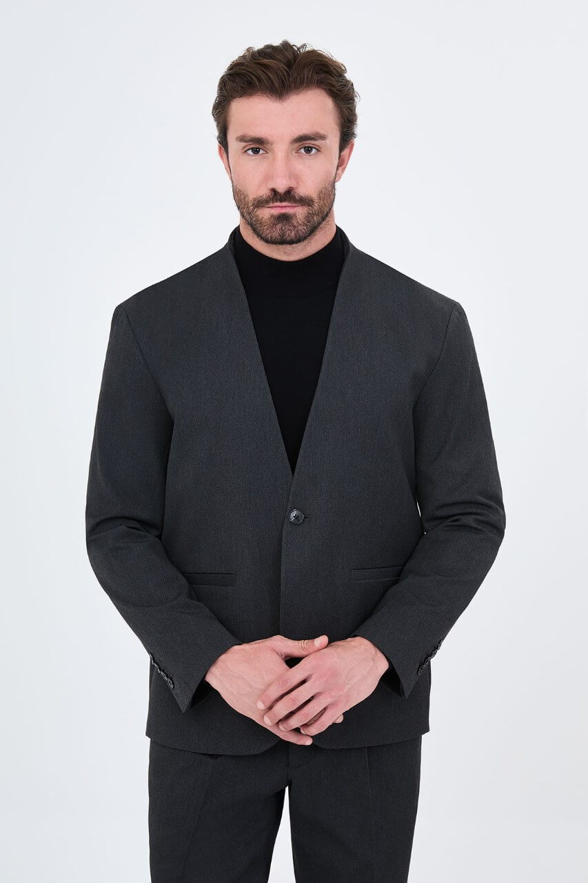 Full-length charcoal grey men's suit styled with a black turtleneck and black leather loafers for a contemporary smart-casual look.