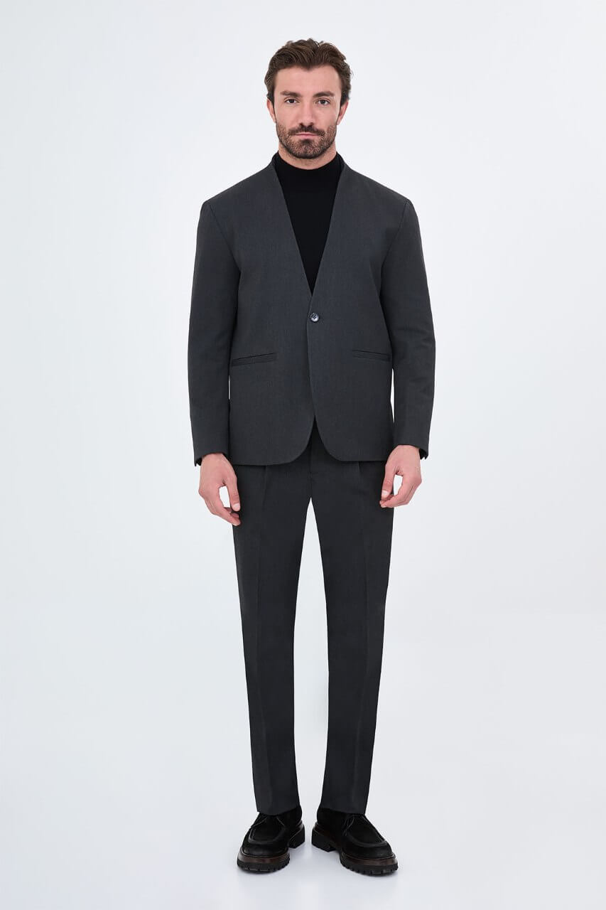 Full-length charcoal grey men's suit styled with a black turtleneck and black leather loafers for a contemporary smart-casual look.