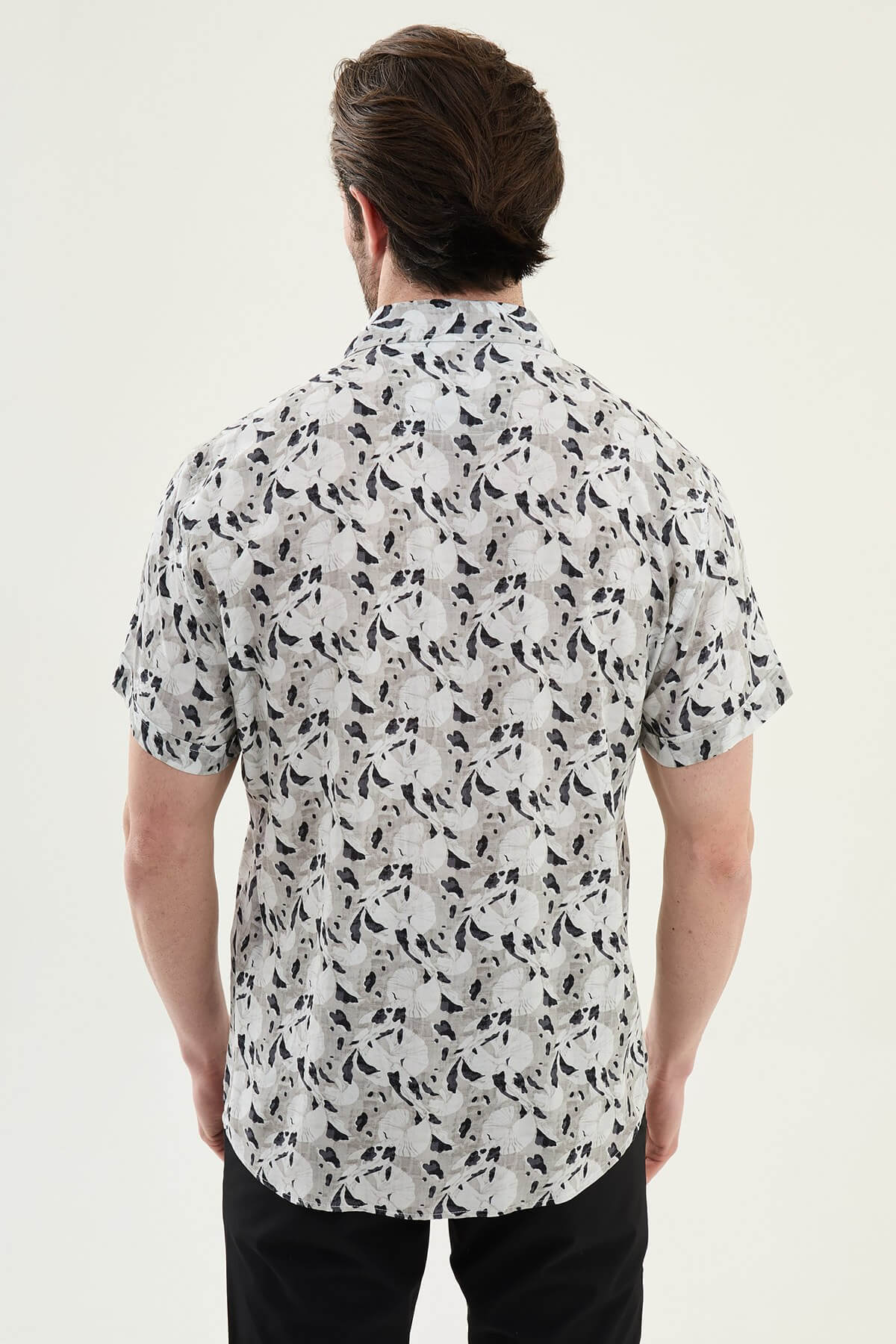 Man wearing a gray patterned short-sleeve summer shirt, front view, styled with casual summer trousers, neutral background.