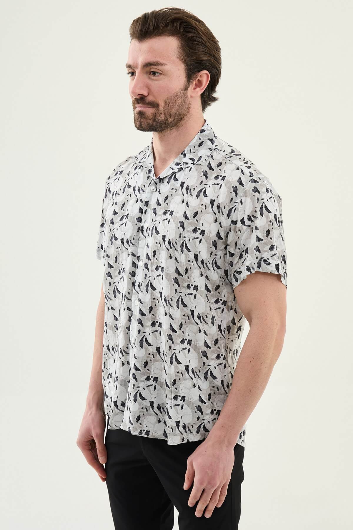 Man wearing a gray patterned short-sleeve summer shirt, front view, styled with casual summer trousers, neutral background.