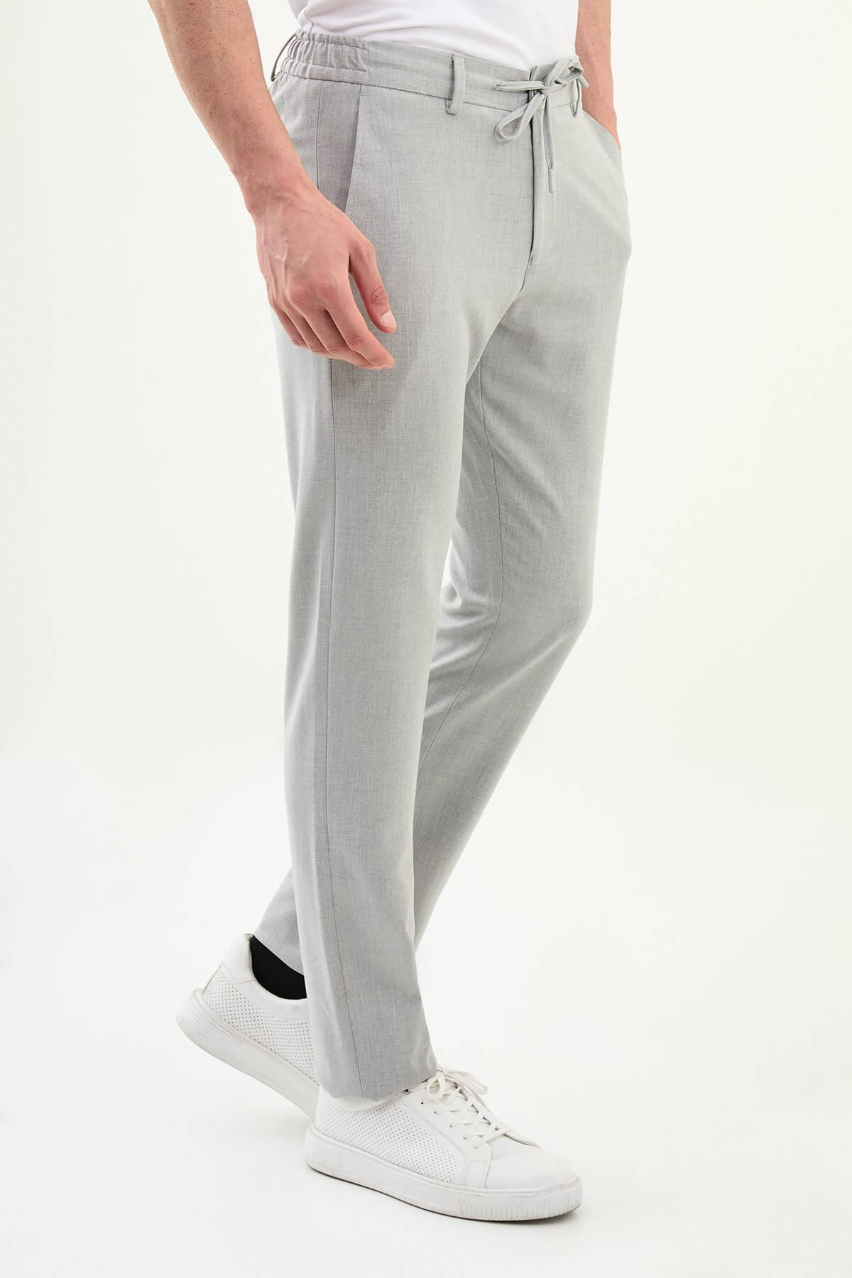 Men wearing gray slim-fit drawstring trousers with elastic waistband, tapered fit, styled with dress shoes and sneakers for versatile summer menswear.