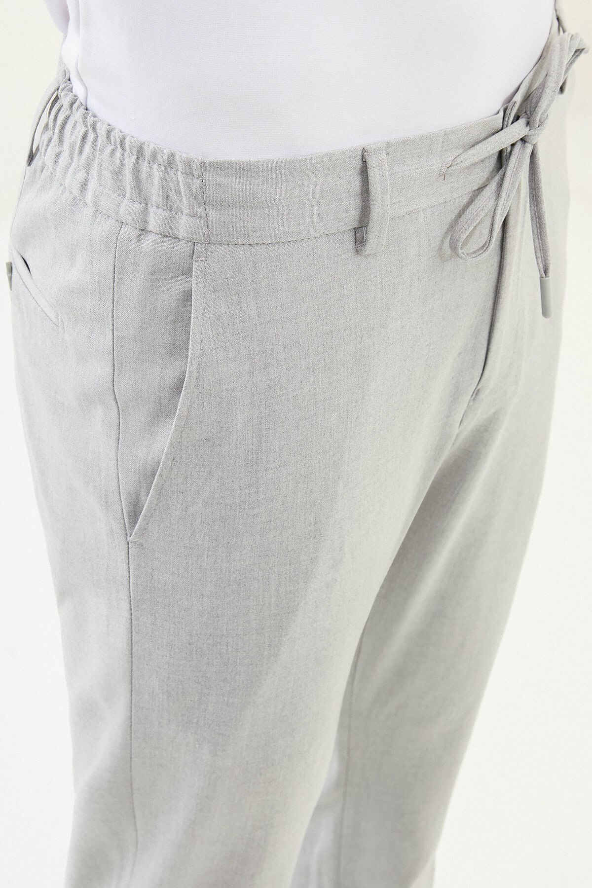 Men wearing gray slim-fit drawstring trousers with elastic waistband, tapered fit, styled with dress shoes and sneakers for versatile summer menswear.