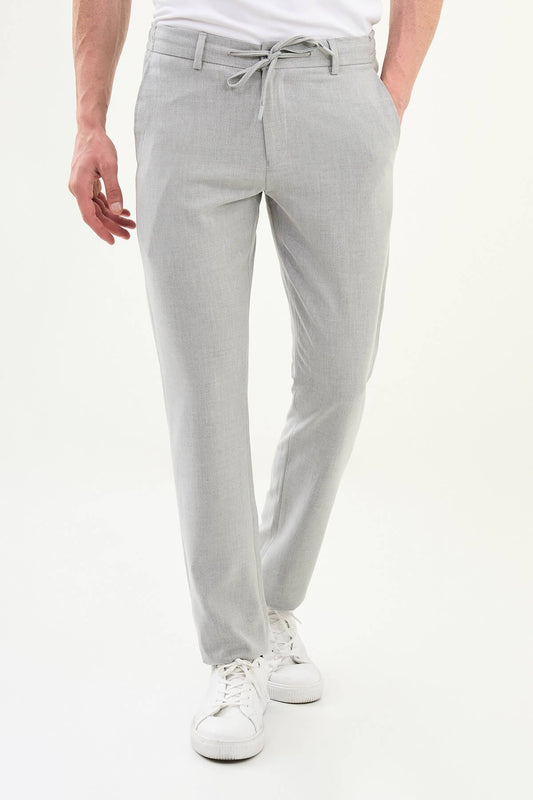 Men wearing gray slim-fit drawstring trousers with elastic waistband, tapered fit, styled with dress shoes and sneakers for versatile summer menswear.