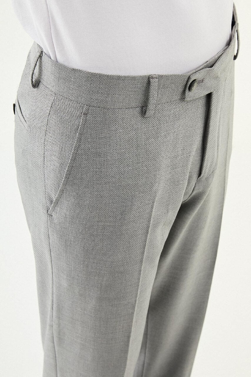 Man wearing gray pleated dress trousers with a straight slim fit, styled with a white dress shirt and black leather shoes.