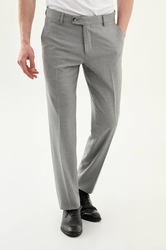 Man wearing gray pleated dress trousers with a straight slim fit, styled with a white dress shirt and black leather shoes.