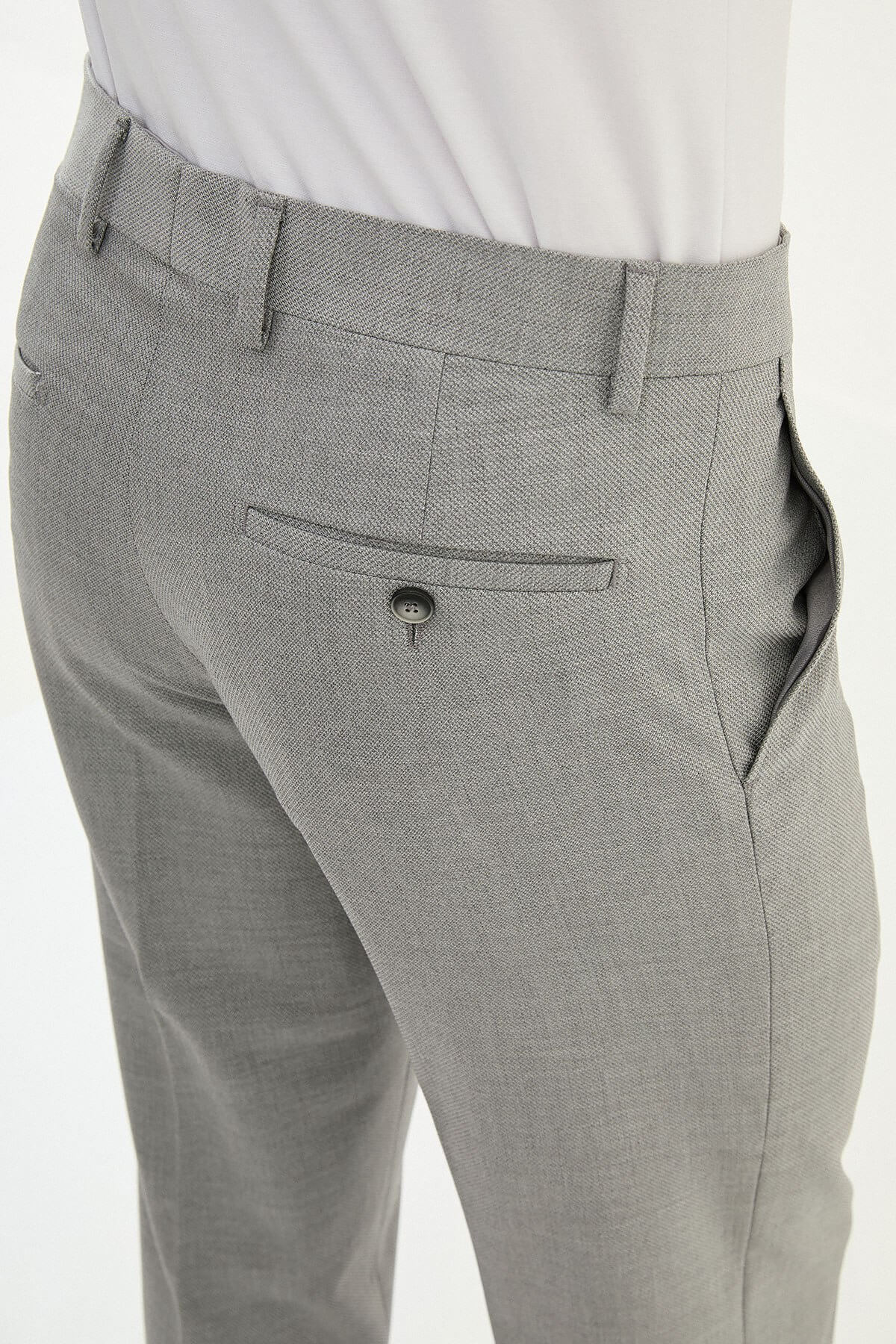 Man wearing gray pleated dress trousers with a straight slim fit, styled with a white dress shirt and black leather shoes.