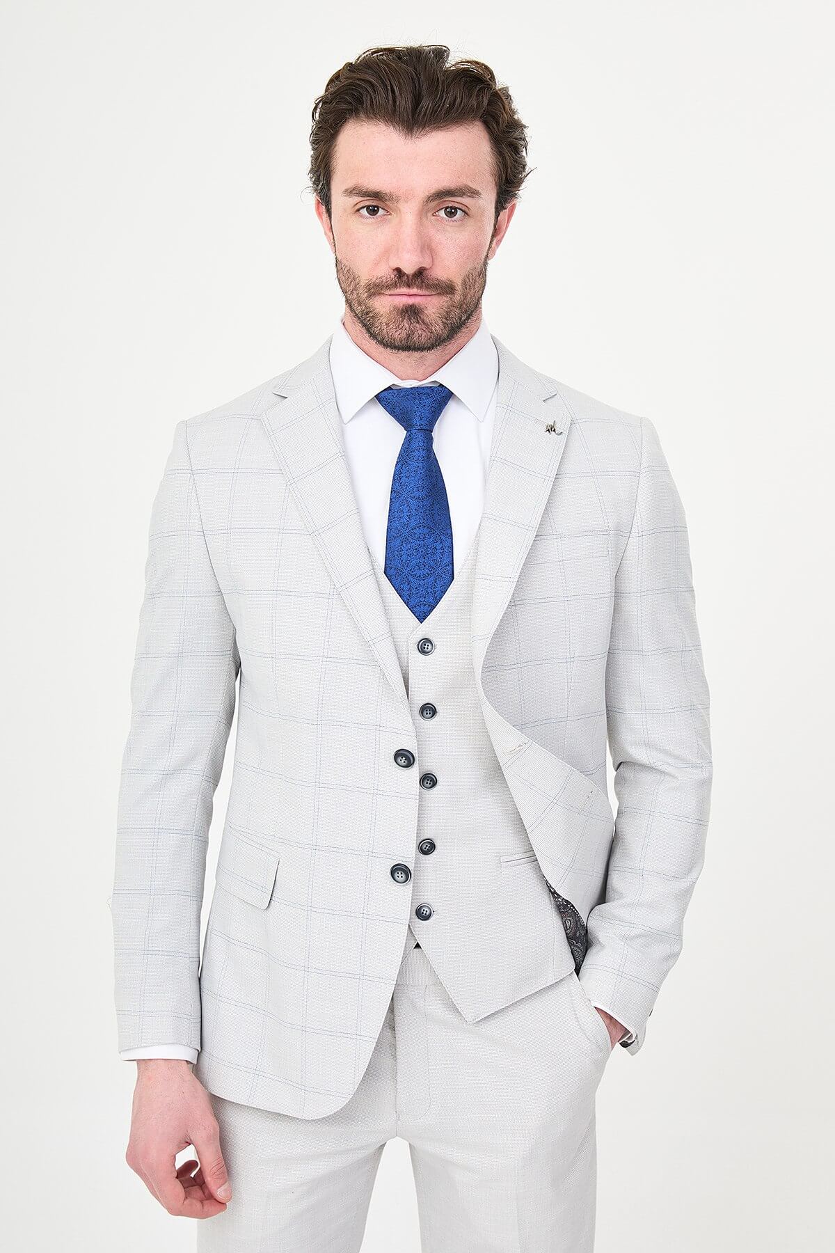 a gray check slim-fit three-piece suit with matching waistcoat and trousers, white dress shirt, royal-blue tie, and black leather Derby shoes.