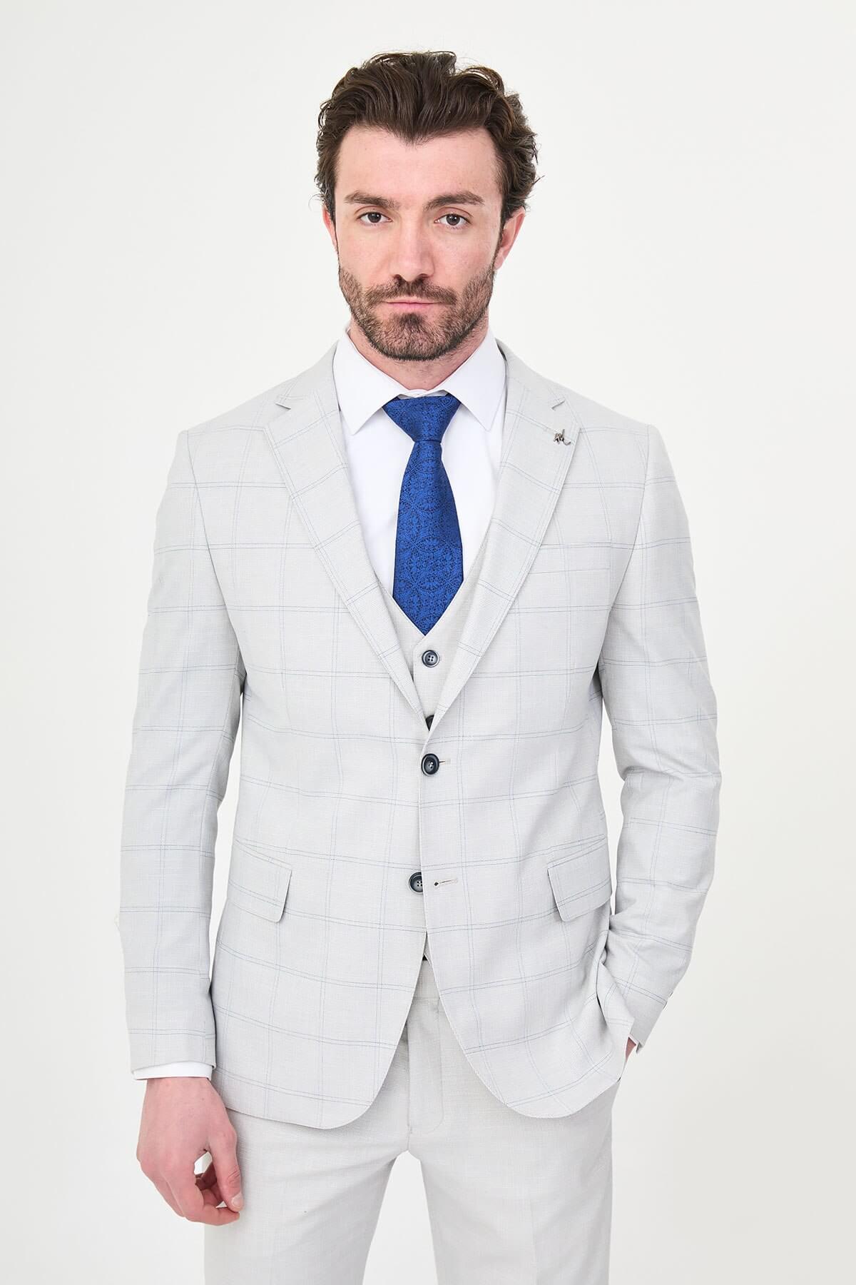 a gray check slim-fit three-piece suit with matching waistcoat and trousers, white dress shirt, royal-blue tie, and black leather Derby shoes.