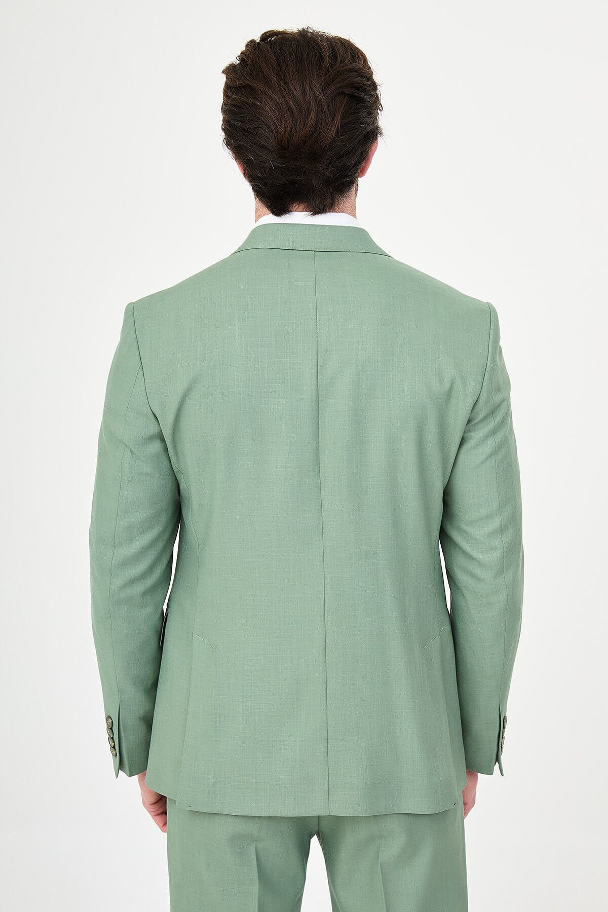 a green slim-fit double-breasted linen-blend suit with peak lapels, matching trousers, an open-collar white shirt, and white leather sneakers.