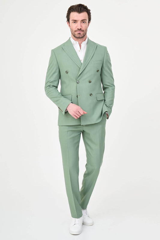 a green slim-fit double-breasted linen-blend suit with peak lapels, matching trousers, an open-collar white shirt, and white leather sneakers.