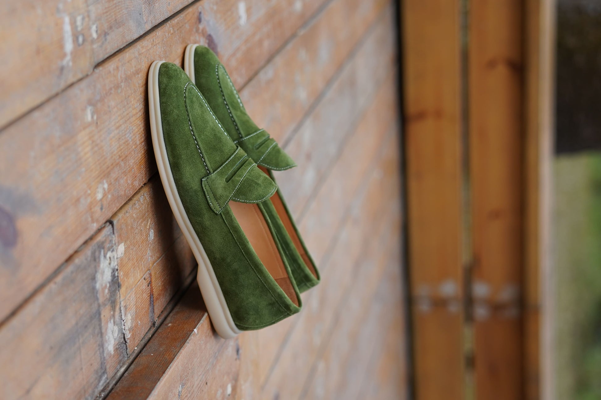 Men’s green suede leather penny loafers featuring classic vamp strap detail and lightweight sole.
