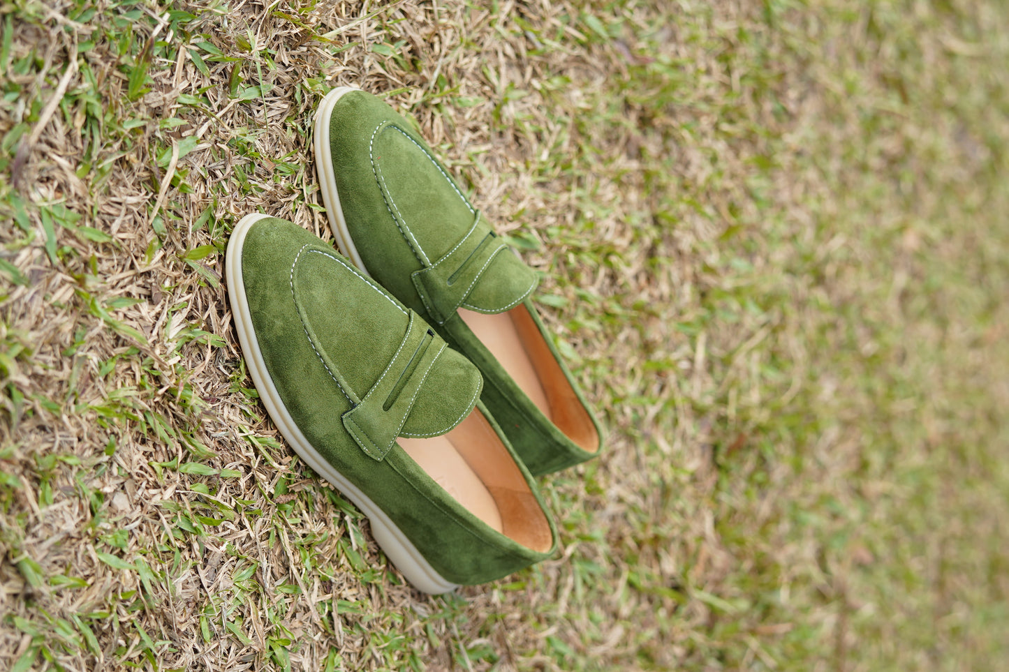 Men’s green suede leather penny loafers featuring classic vamp strap detail and lightweight sole.