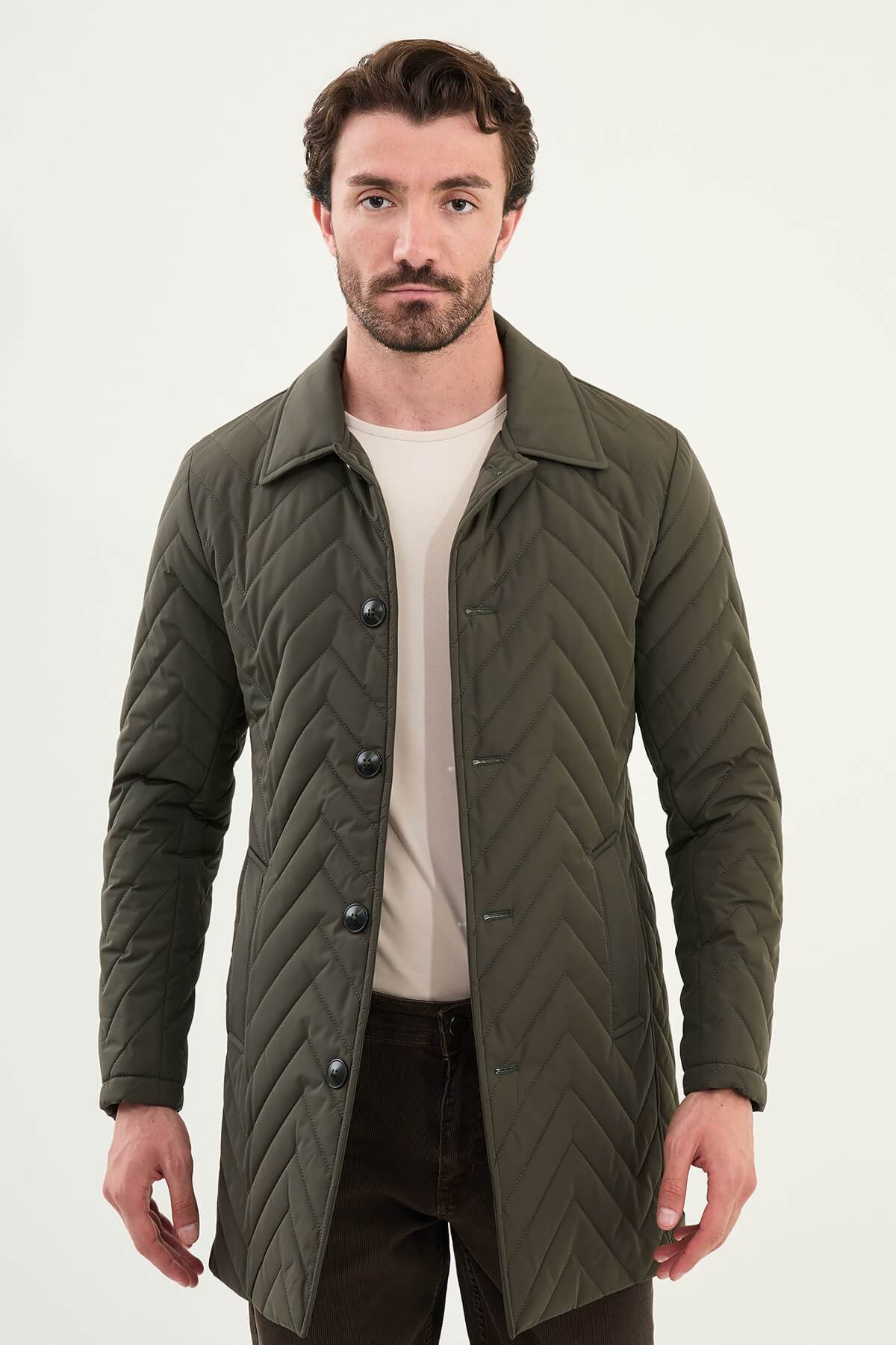 Man wearing a slim fit green quilted car coat with button closure, styled with brown trousers and beige sneakers.