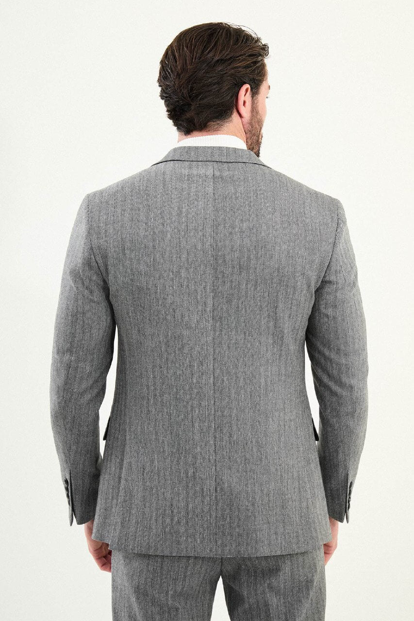 Men’s gray herringbone slim-fit single-breasted suit with structured shoulders and tailored waist, high-wool blend fabric with stretch, styled with a light gray fine-gauge turtleneck for winter.