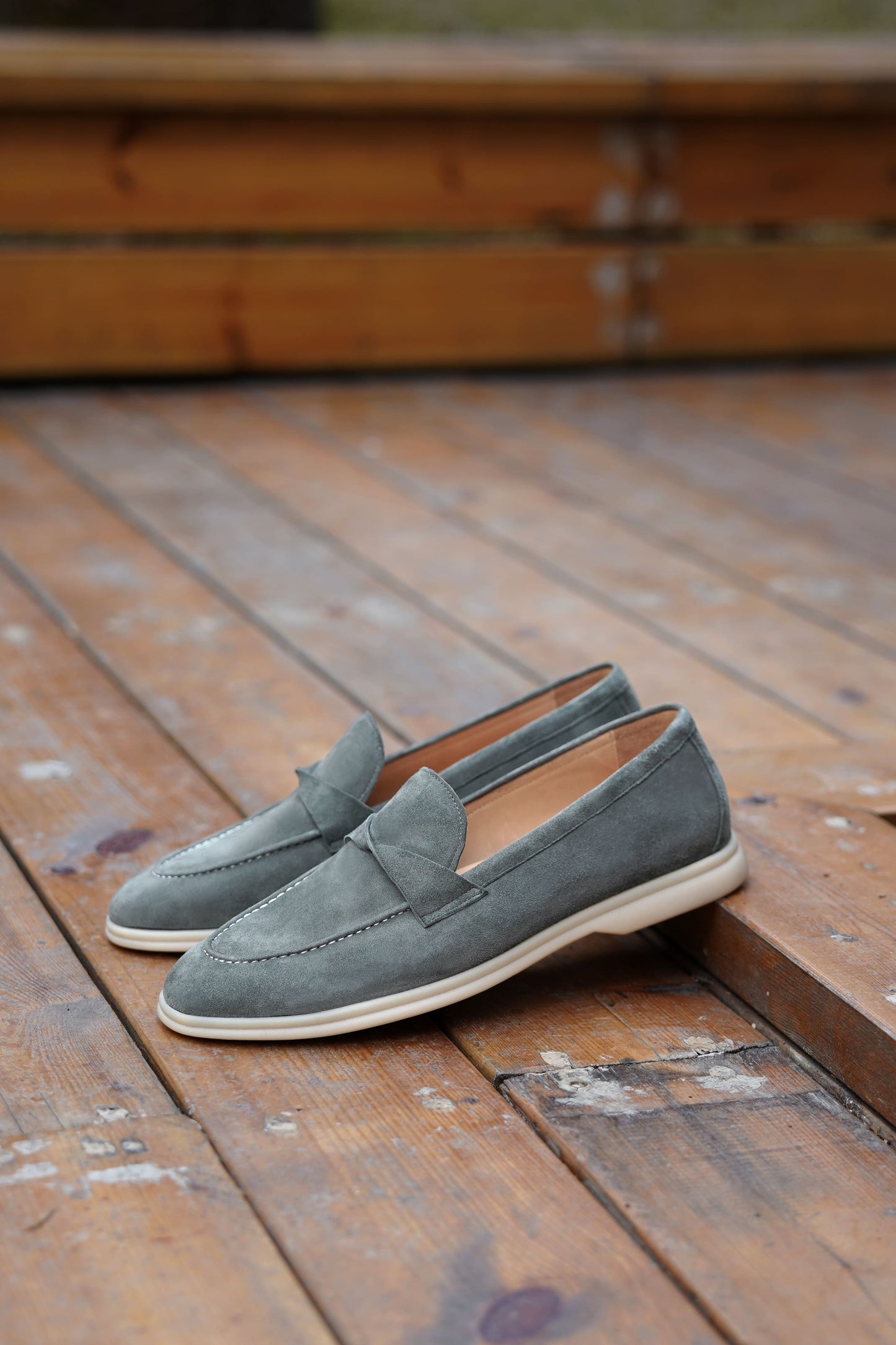 Men’s grey suede leather penny loafers featuring classic vamp strap detail and lightweight cream sole.