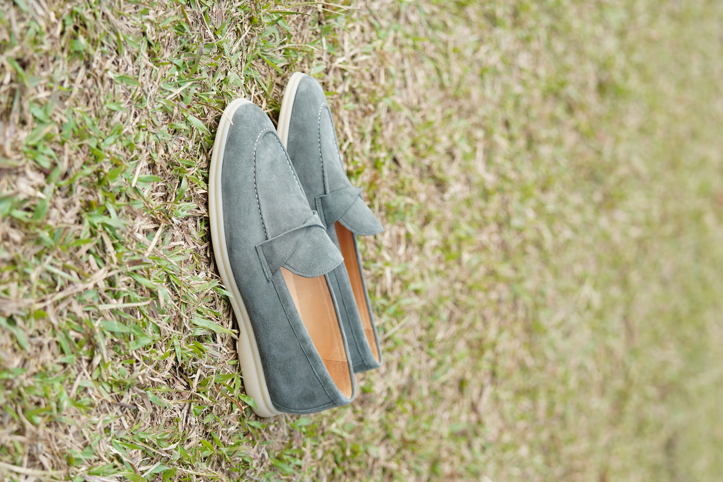 Men’s grey suede leather penny loafers featuring classic vamp strap detail and lightweight cream sole.