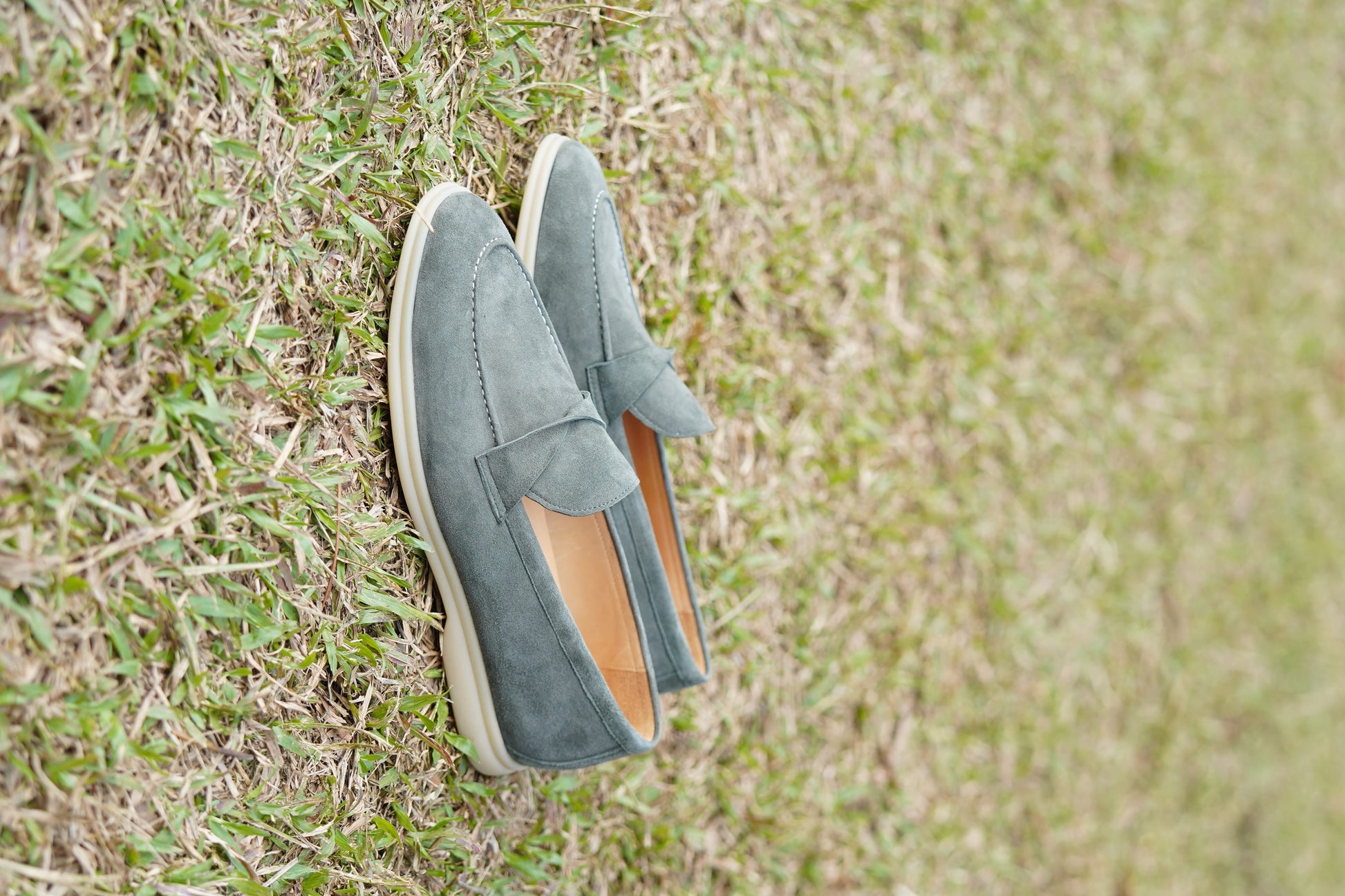 Men’s grey suede leather penny loafers featuring classic vamp strap detail and lightweight cream sole.