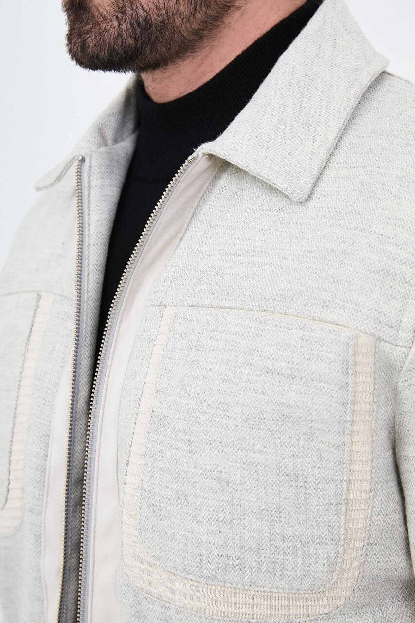 Light grey men's casual jacket styled with a black top and dark trousers.