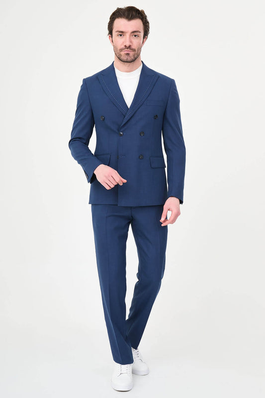 an indigo slim-fit double-breasted linen-blend suit with peak lapels, contrast pick stitching, matching trousers, a white knit top, and white leather sneakers.