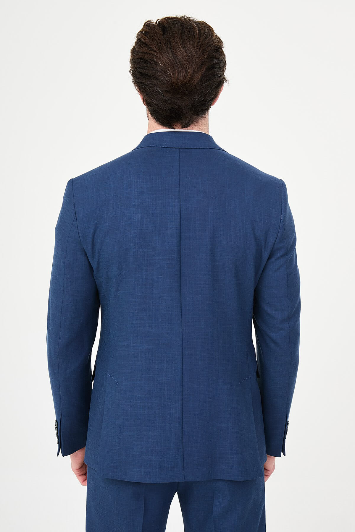 an indigo slim-fit double-breasted linen-blend suit with peak lapels, contrast pick stitching, matching trousers, a white knit top, and white leather sneakers.