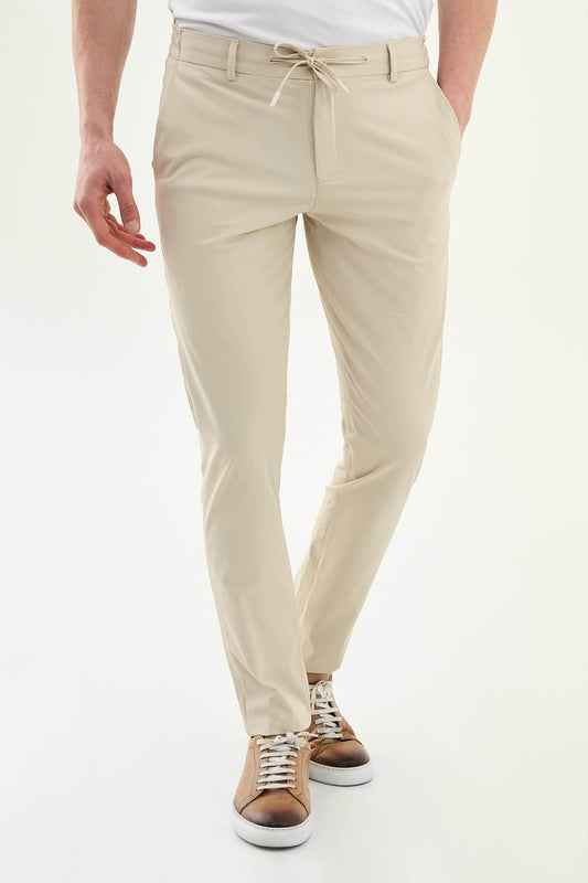 Man wearing khaki slim-fit summer trousers styled with a white polo shirt and brown loafers.