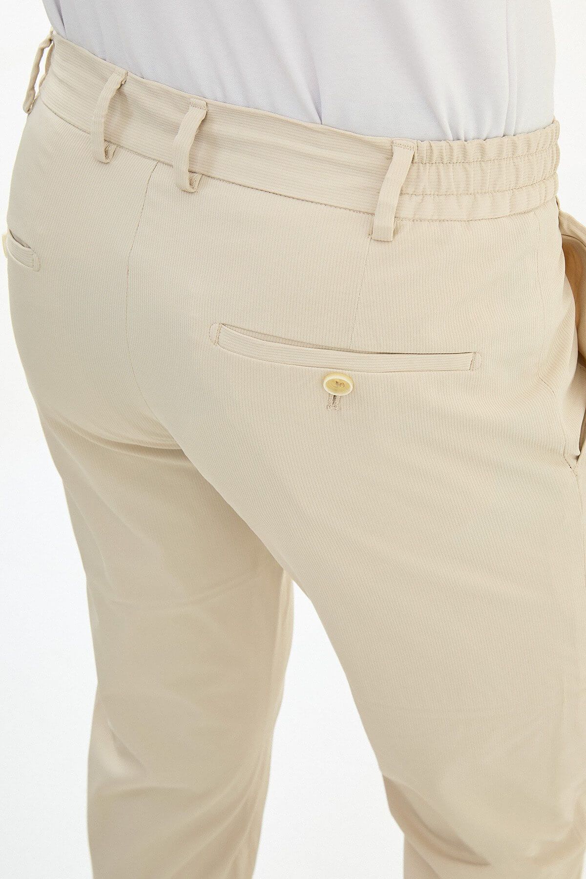Man wearing khaki slim-fit summer trousers styled with a white polo shirt and brown loafers.