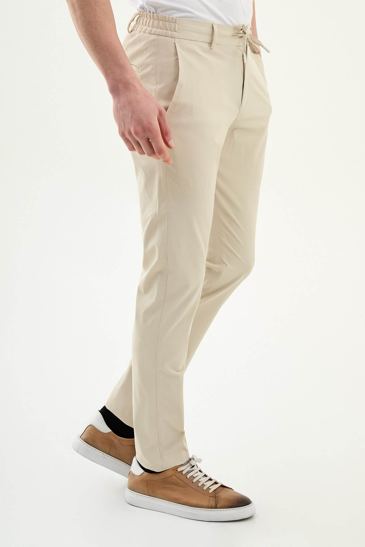 Man wearing khaki slim-fit summer trousers styled with a white polo shirt and brown loafers.