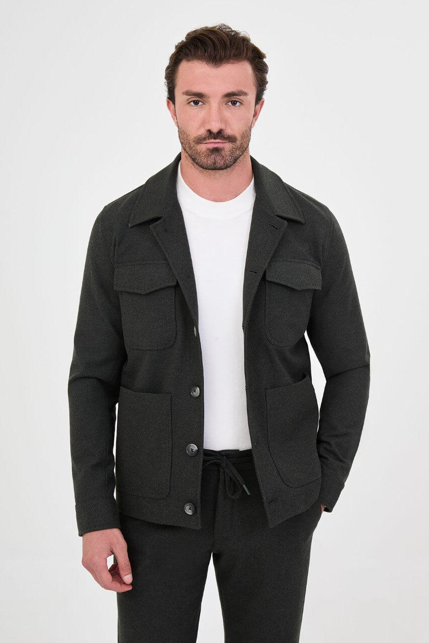 Men's dark khaki fall jacket styled with a white crew-neck shirt and matching trousers.