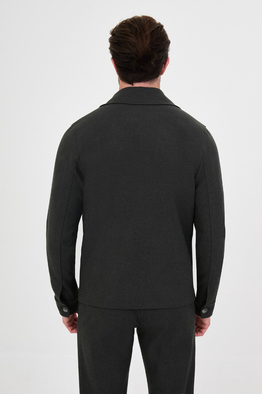Men's dark khaki fall jacket styled with a white crew-neck shirt and matching trousers.