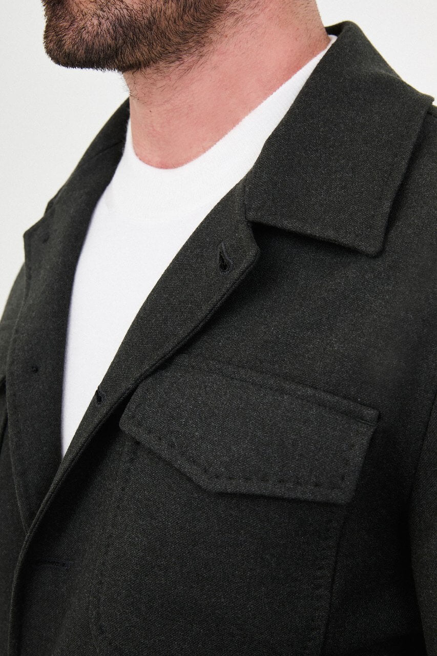Men's dark khaki fall jacket styled with a white crew-neck shirt and matching trousers.